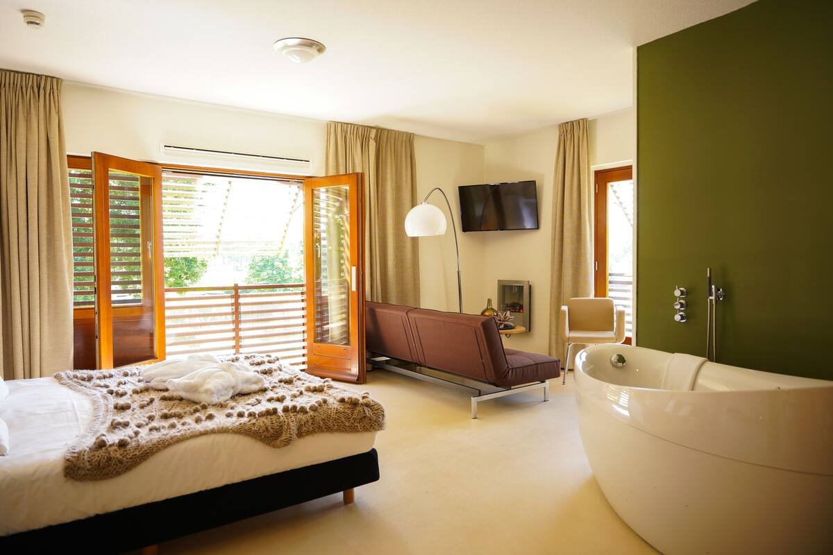 Ein Schlafzimmer mit einem großen Bett, einer Badewanne, einem Sessel und einem Fernseher.