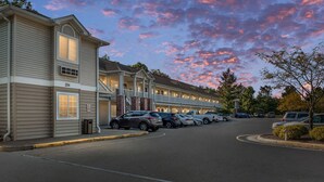 A motel with a row of rooms, a covered parking area, and a street view.