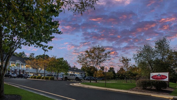 A hotel with a sign reading "Affordable Suites by Wyndham" in front of a parking lot with cars and a road.
