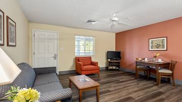 A living room with a sofa, armchair, coffee table, TV, and dining table with chairs.