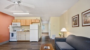 A compact living space with a kitchenette, a ceiling fan, a sofa, and a coffee table.