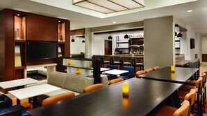A modern hotel lobby with a bar area, seating arrangements, and a television. - Hyatt House Denver Airport (Denver)
