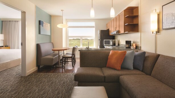 A modern hotel room with a living area, kitchenette, and a large window offering a view. - Hyatt House Denver Airport (Denver)