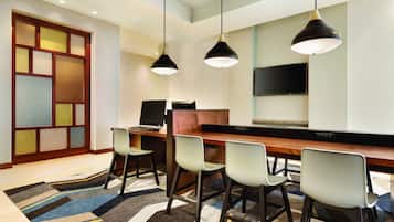 A modern hotel lobby with a bar area, seating, and a flat-screen TV.