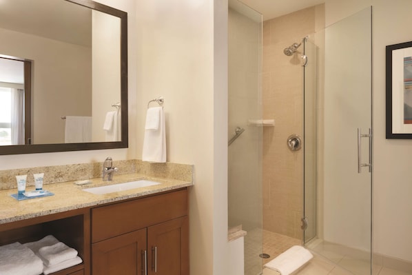 Un baño con lavabo, espejo y zona de ducha.