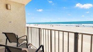 A balcony with a view of a beach, a chair, and a railing. - Sands Beach Club (Myrtle Beach)