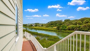 A balcony with a view of a river, greenery, and distant houses. - Sands Beach Club (Myrtle Beach)