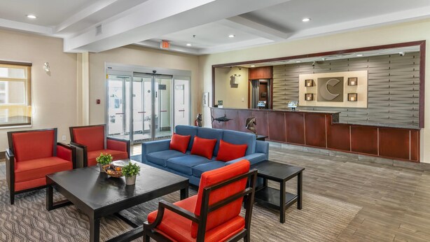 A lobby with a reception desk, a blue sofa with red cushions, and red armchairs. - Comfort Inn (Dawson Creek)