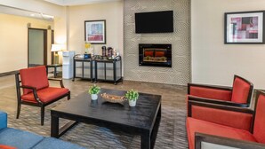 A hotel lobby with a fireplace, seating area, and a coffee station. - Comfort Inn (Dawson Creek)