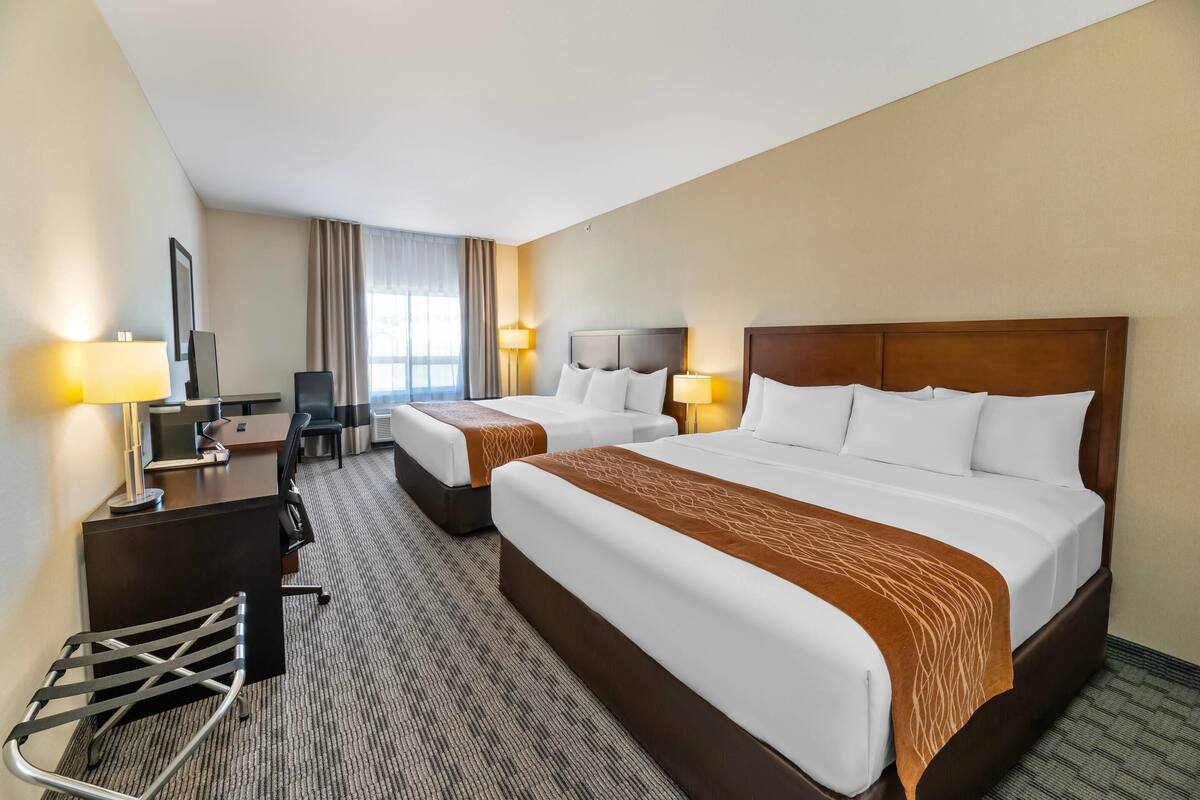 Une chambre d’hôtel avec deux lits, un bureau, une chaise et un téléviseur.