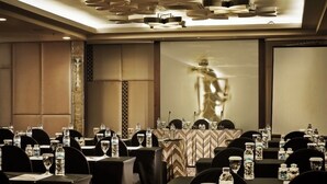 Un salón de conferencias con mesas dispuestas para una reunión, equipado con micrófonos, botellas de agua y vasos.