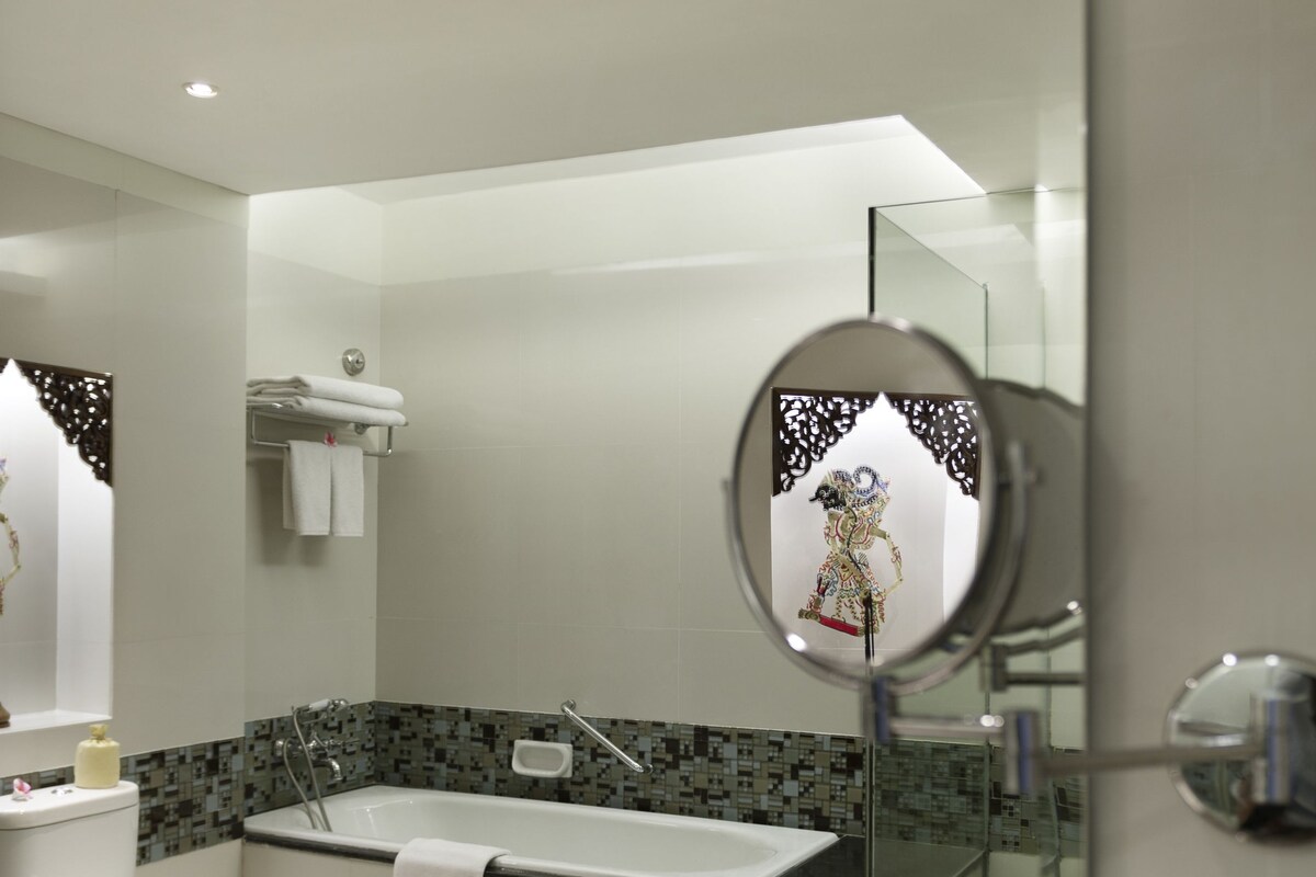 Un baño moderno con un espejo grande, una bañera y un lavabo.