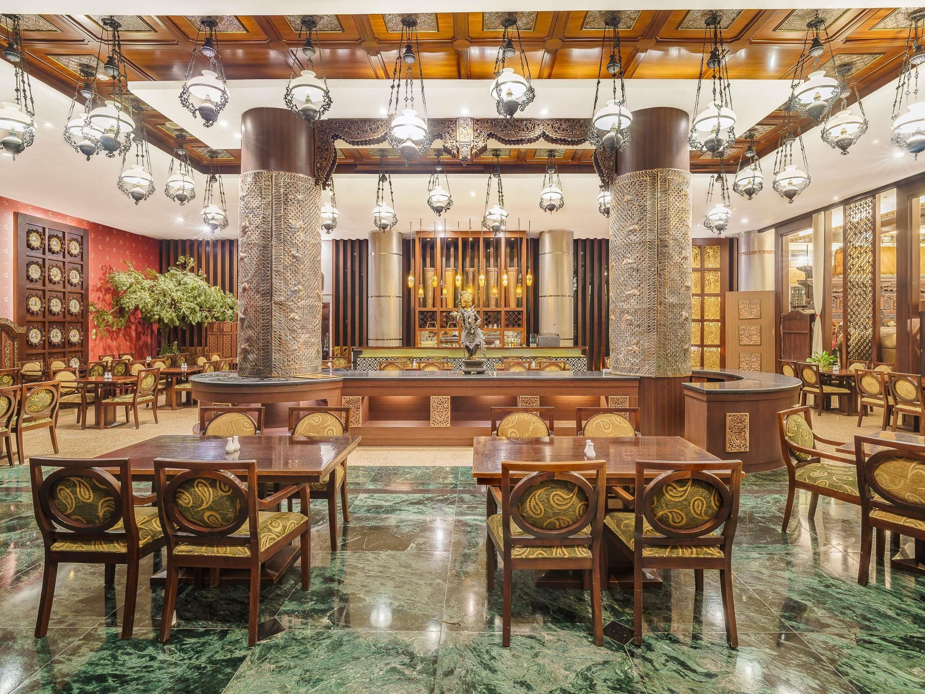 A spacious lobby with a central bar area, marble flooring, and traditional decor.
