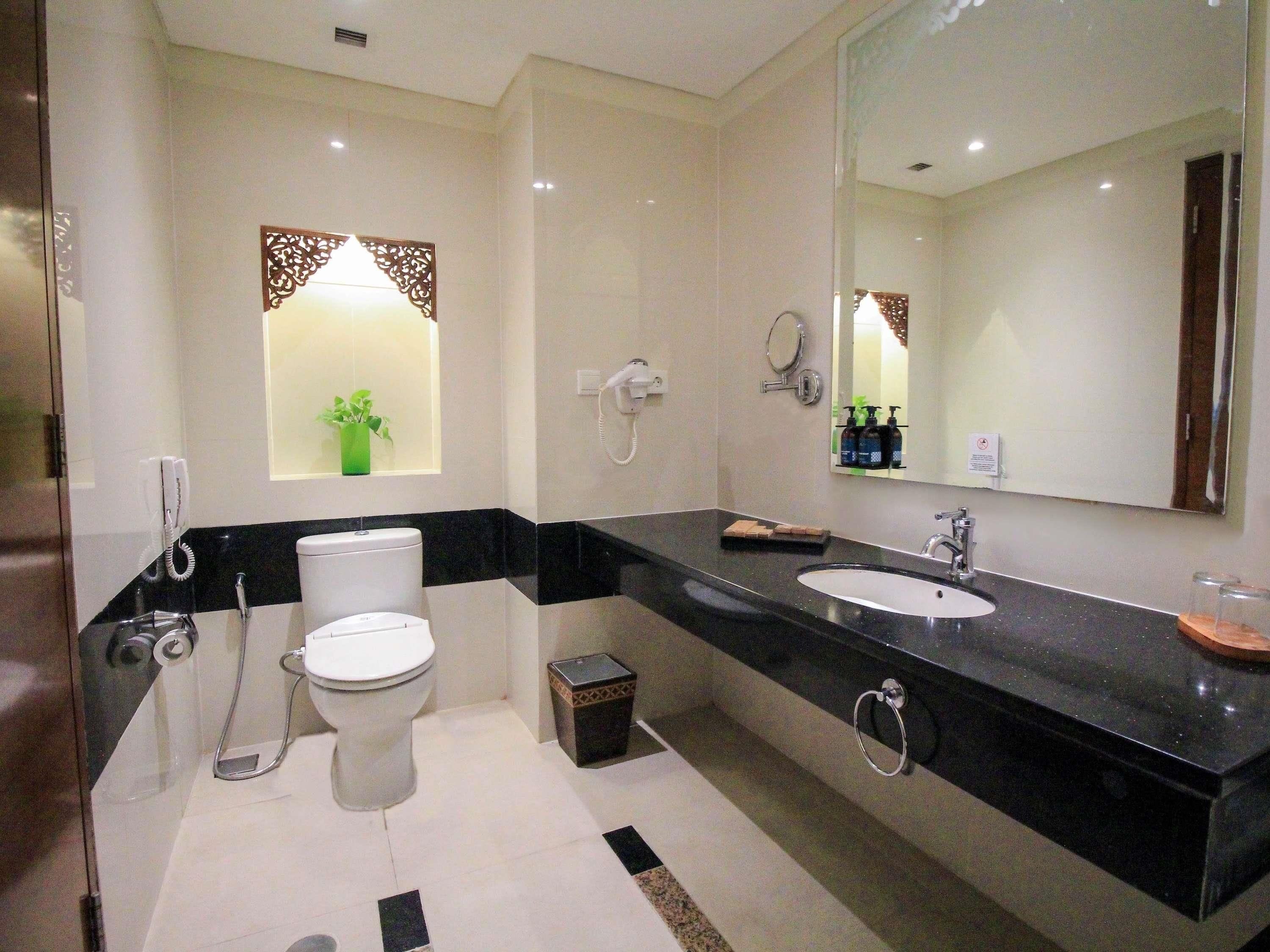 Un baño moderno con inodoro, bidé, lavamanos y un espejo grande.