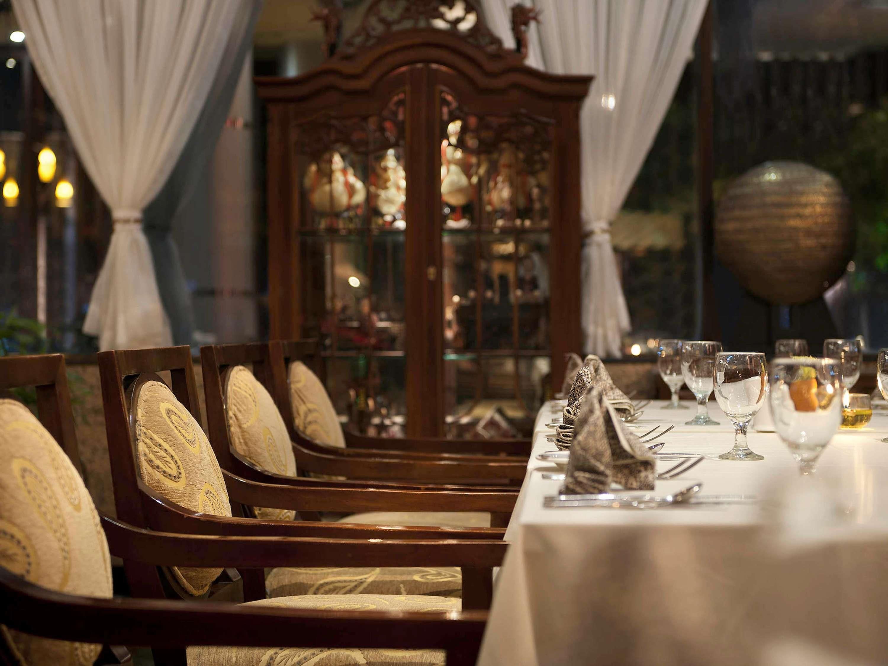 Une salle à manger élégante, avec une longue table, des chaises dotées de coussins à motifs et un buffet décoratif en arrière-plan.