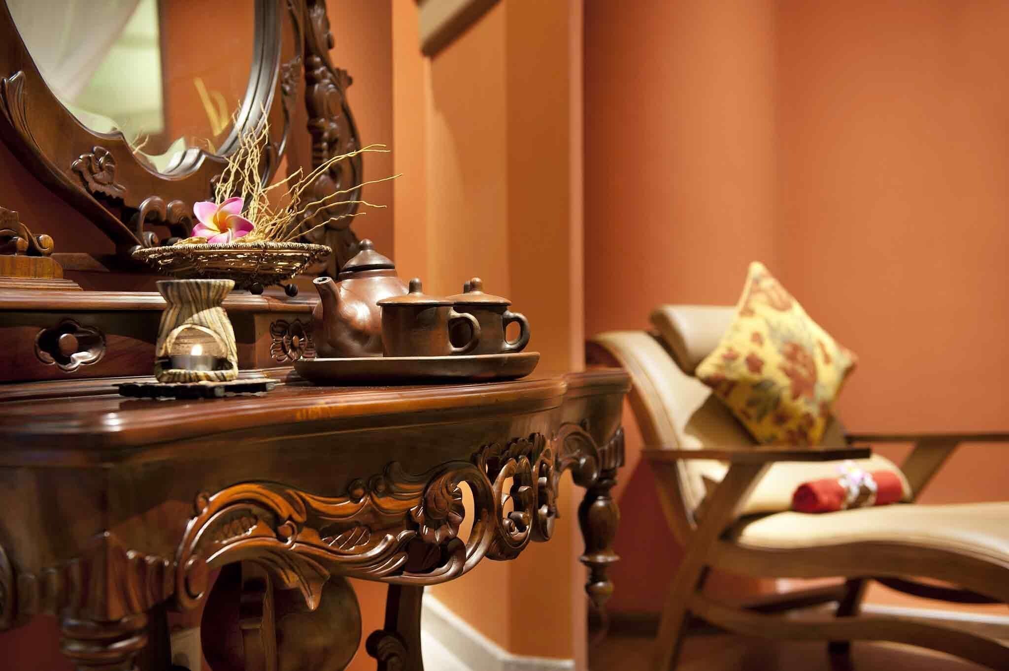 A wooden dresser with a mirror, a teapot, and a small vase with dried plants.