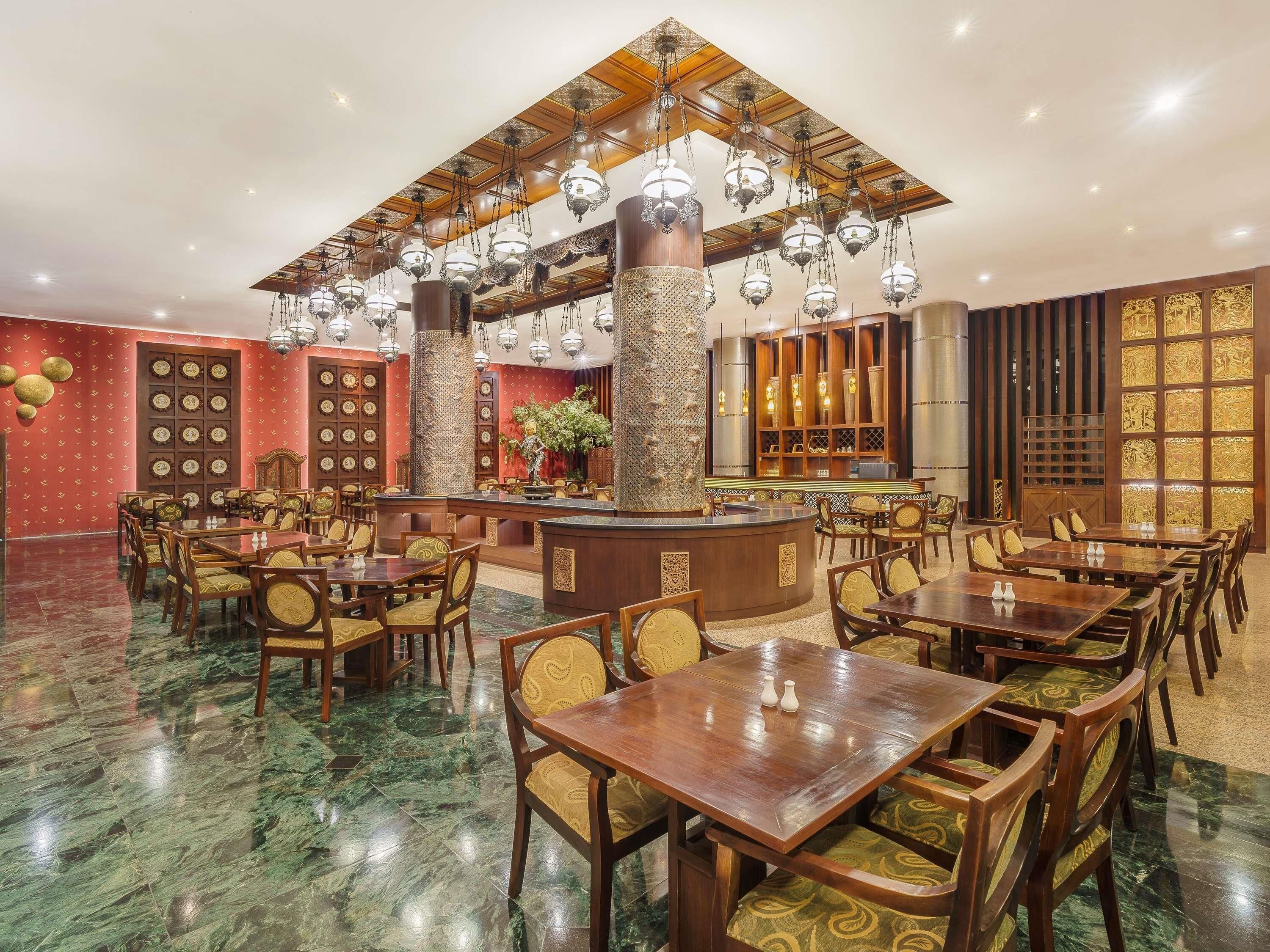 A restaurant with multiple dining tables and chairs, a bar area, and decorative wall panels.