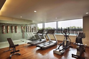 A gym with treadmills, an elliptical, and a bench.