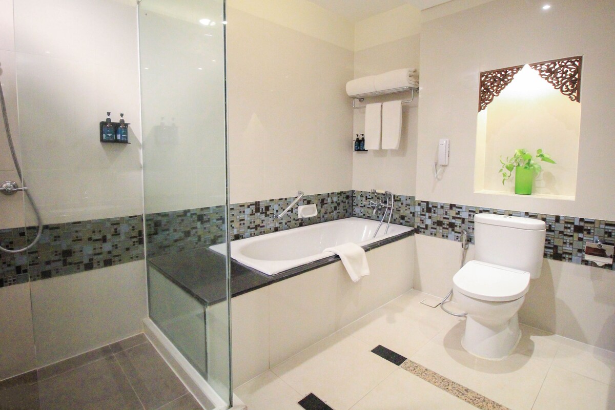 Un baño moderno con ducha envuelta en vidrio, una bañera independiente y un inodoro.
