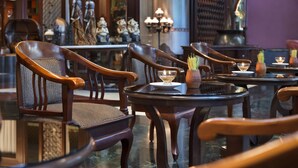 Interior de restaurante con sillas y mesas de madera, y estatuas decorativas.