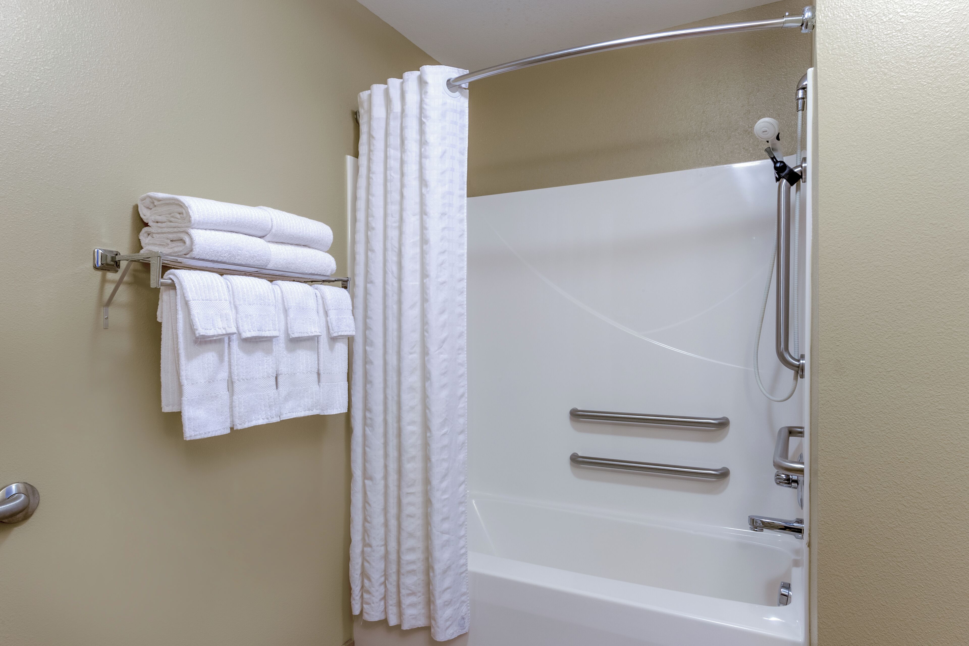 Une salle de bain équipée d’une baignoire, d’une douche et d’un porte-serviettes avec des serviettes pliées.