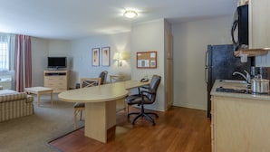 Ett kompakt hotellrum med en matplats, ett litet kök och en tv.