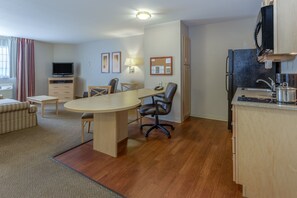Une chambre d’hôtel compacte comprenant un coin repas, une kitchenette et un téléviseur.