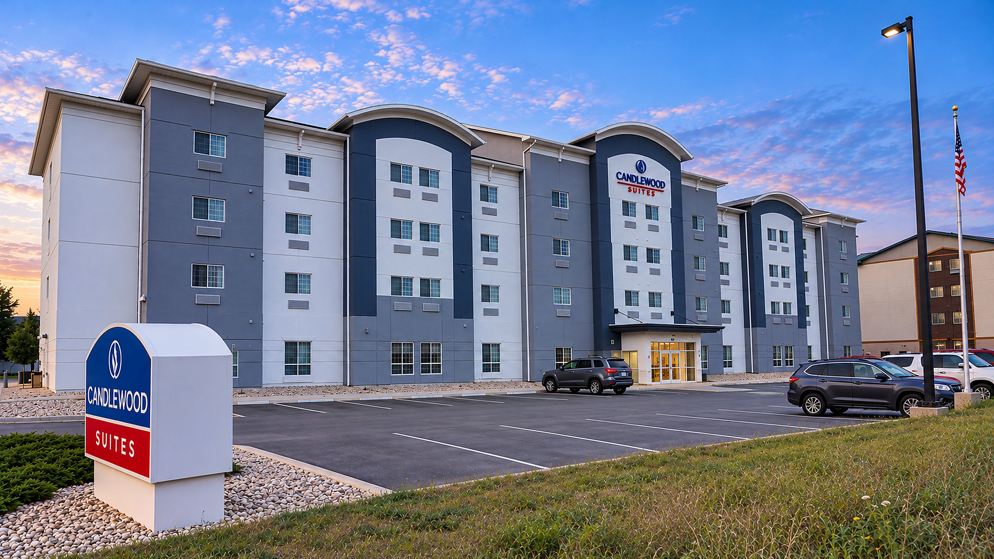A multi-story hotel with a parking lot and a sign indicating 'Candlewood Suites.'