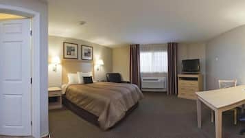 Een hotelkamer met een bed, nachtkastjes, een bureau, een stoel, een televisie en een airconditioning.