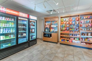 A convenience store with refrigerated beverage dispensers, snack shelves, and a microwave. - Candlewood Suites Minot by IHG (Minot)