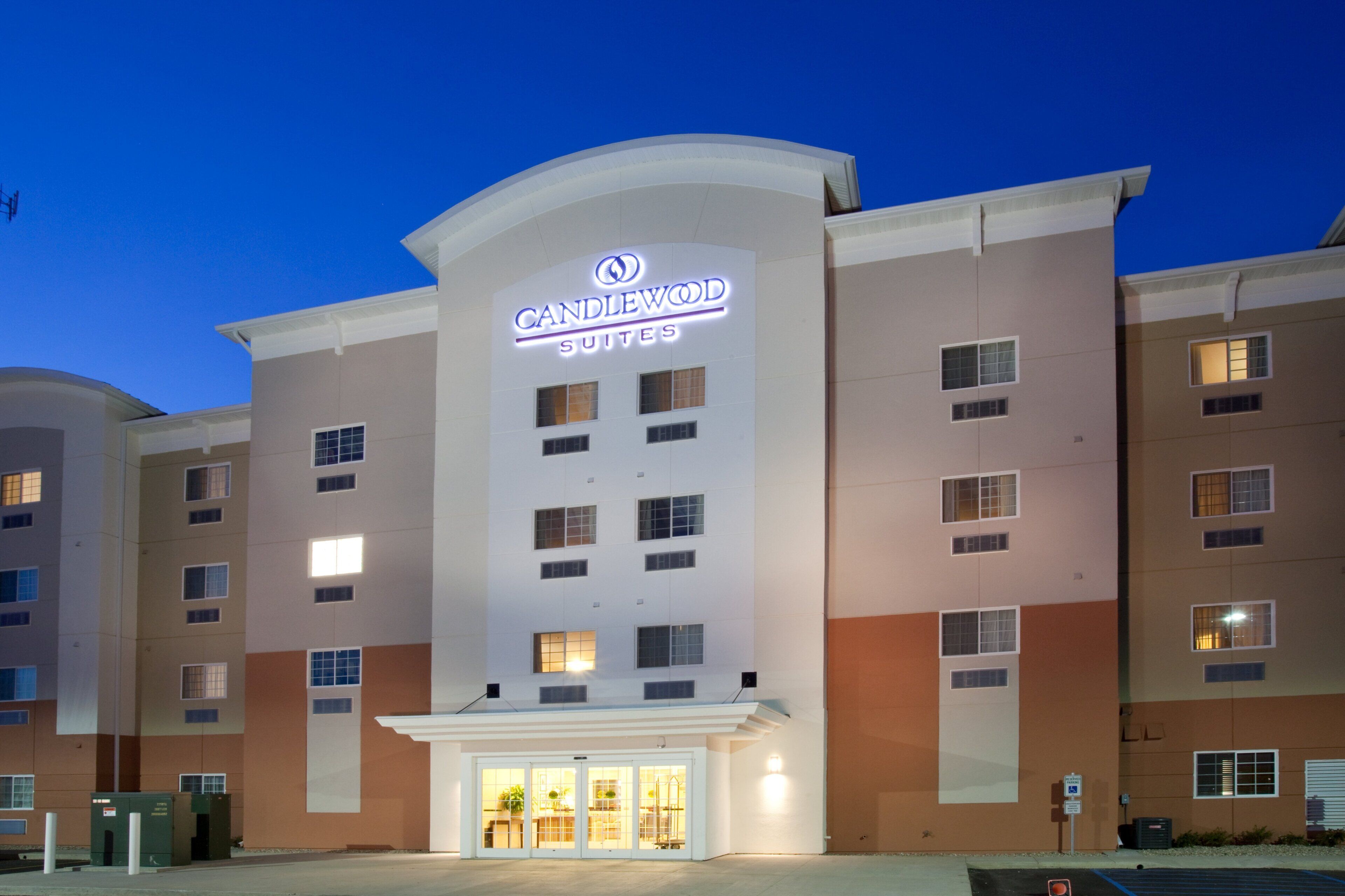 A hotel with a prominent 'CANDLEWOOD SUITES' sign, multiple windows, and a gated entrance.