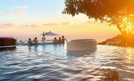 Una piscina al aire libre, sombrillas, sillones reclinables de piscina