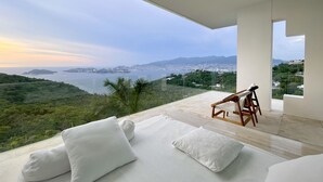 A modern room with a large balcony overlooking a coastal cityscape and hills. - Encanto Acapulco (Acapulco)