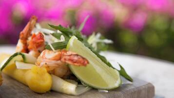A wooden board with shrimp, pineapple, and lime.