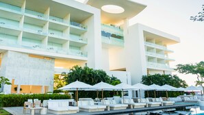 A modern hotel with a pool area, lounge chairs, and umbrellas. - Encanto Acapulco (Acapulco)
