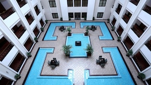 A multi-level hotel with a central courtyard featuring a pool with geometric patterns, surrounded by seating areas and potted plants. - Greenpark Chennai (Chennai)