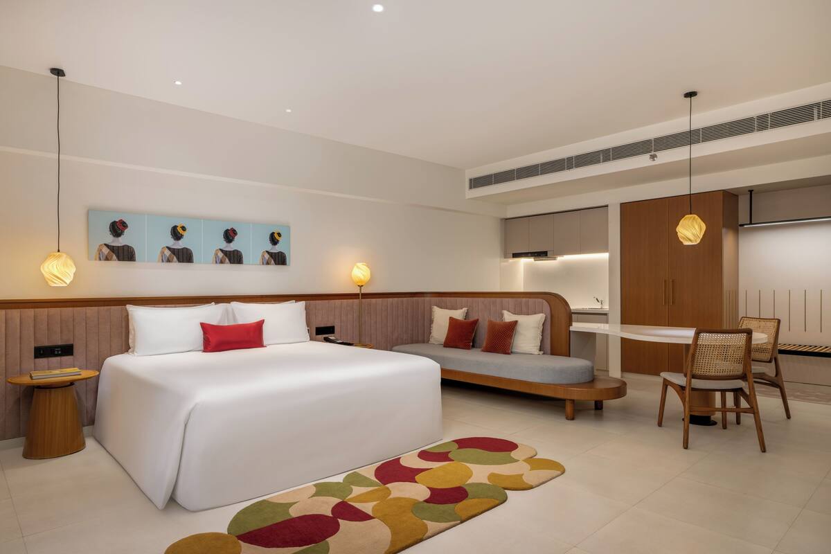 Una habitación de hotel moderna con una cama grande, un sofá, una mesa de comedor y una zona de estar.