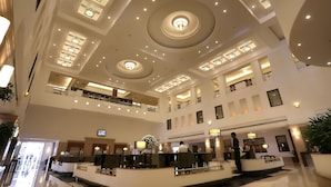 A multi-level hotel lobby with a central reception desk, multiple floors, and a modern ceiling design with recessed lighting. - Greenpark Chennai (Chennai)
