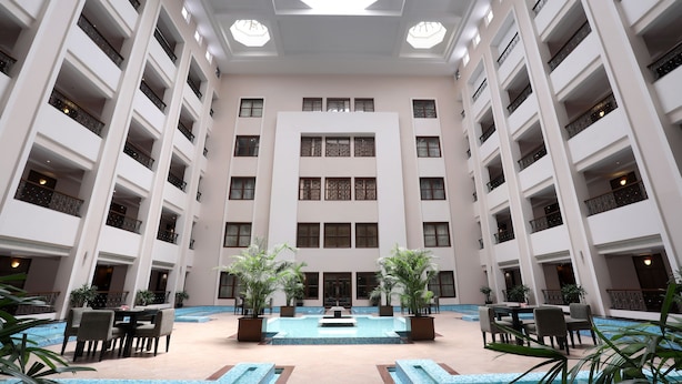 A multi-story hotel atrium with a central pool, multiple balconies, and indoor plants. - Greenpark Chennai (Chennai)