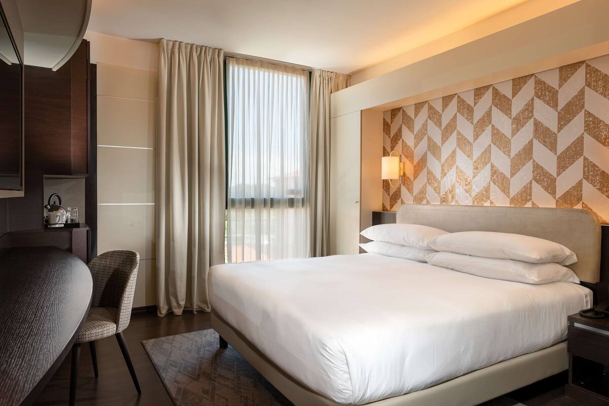 Una habitación de hotel con una cama grande, un escritorio y una silla.
