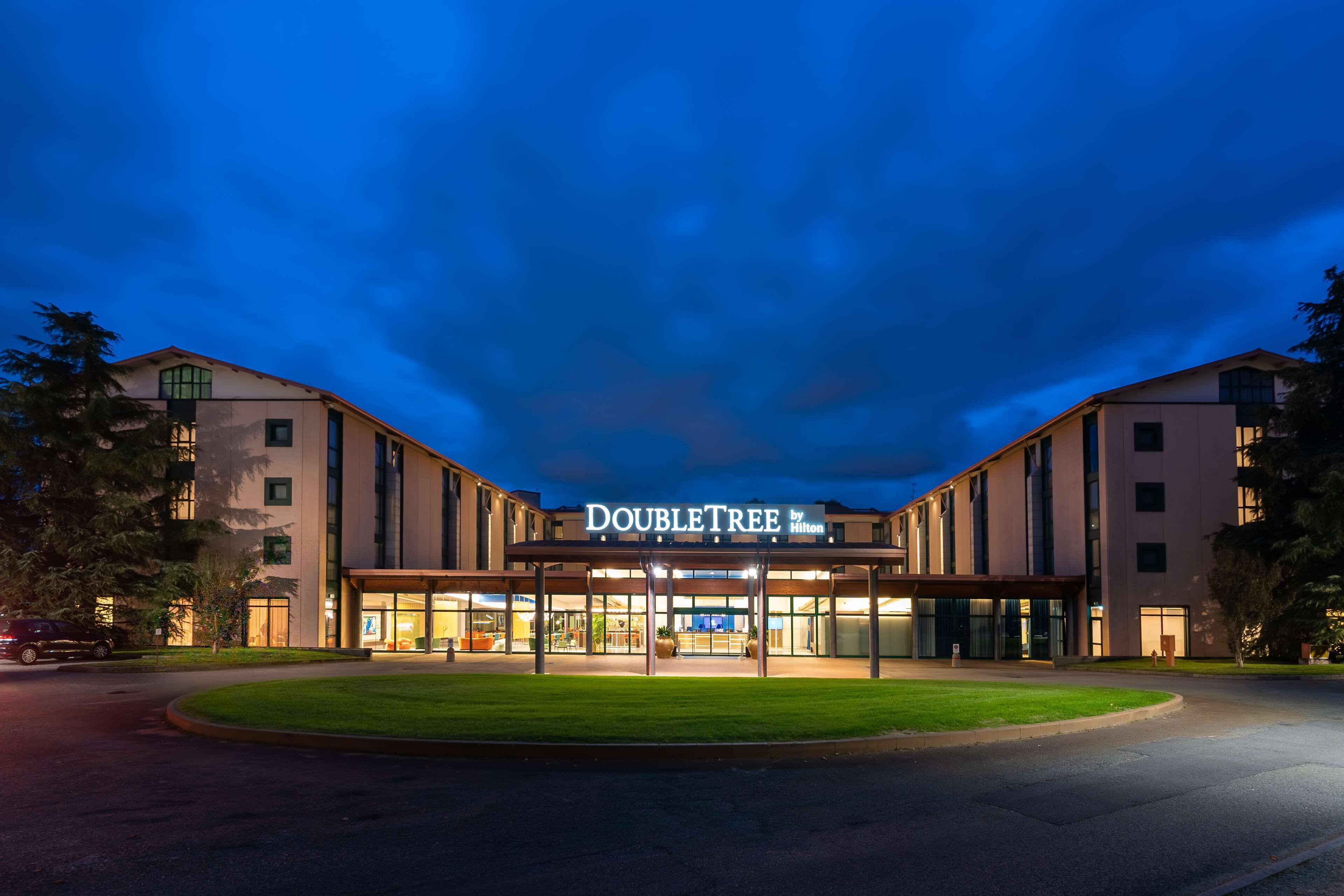 A DoubleTree by Hilton hotel with a modern facade, large glass entrance, and a well-maintained lawn.