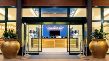 L’entrée d’un hôtel avec un comptoir d’accueil, de grands pots de plantes et un intérieur aux tons bleus.