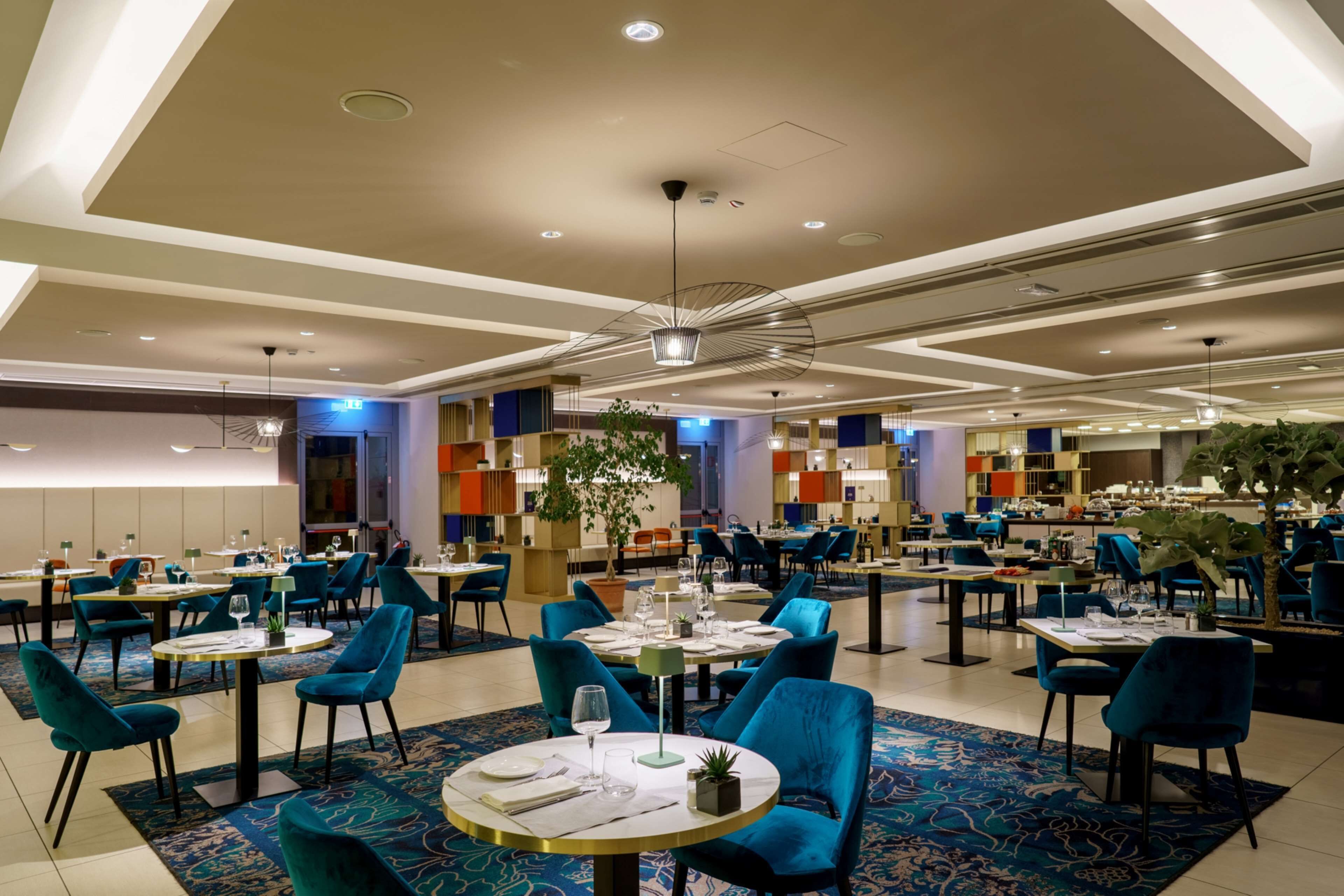Un comedor moderno con mesas redondas, sillas azules y una alfombra estampada.