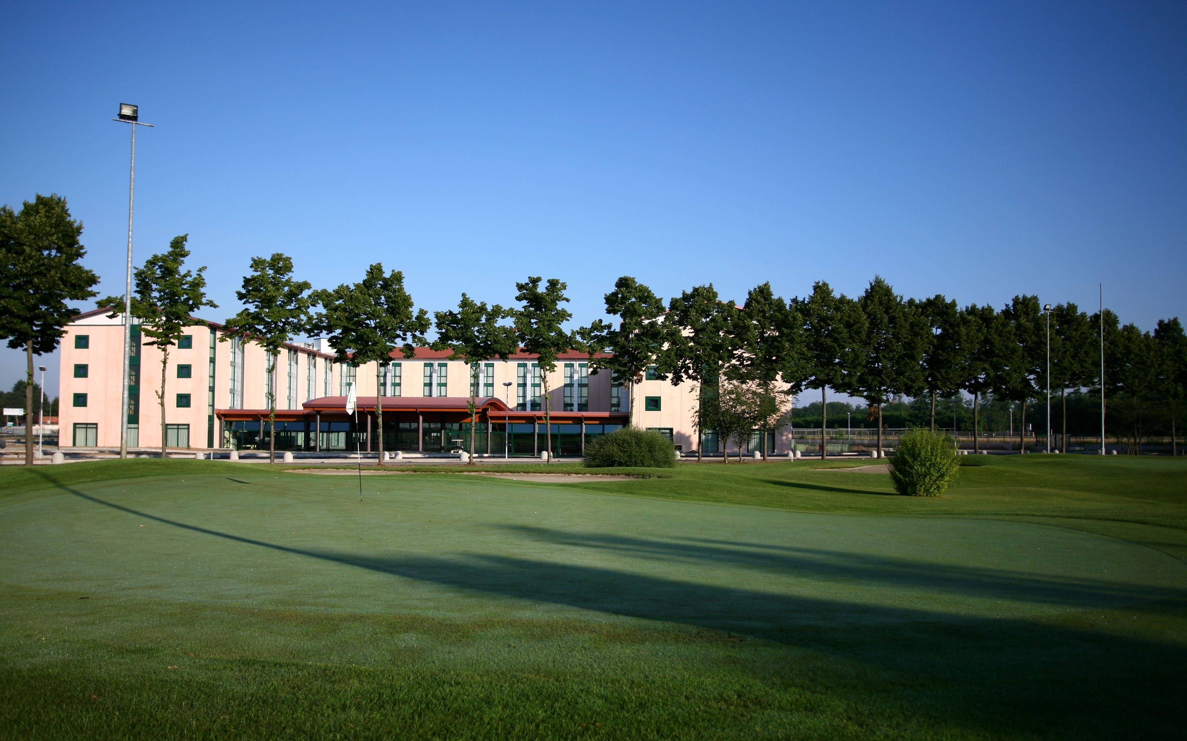 A golf course with a clubhouse featuring multiple windows and a red roof.