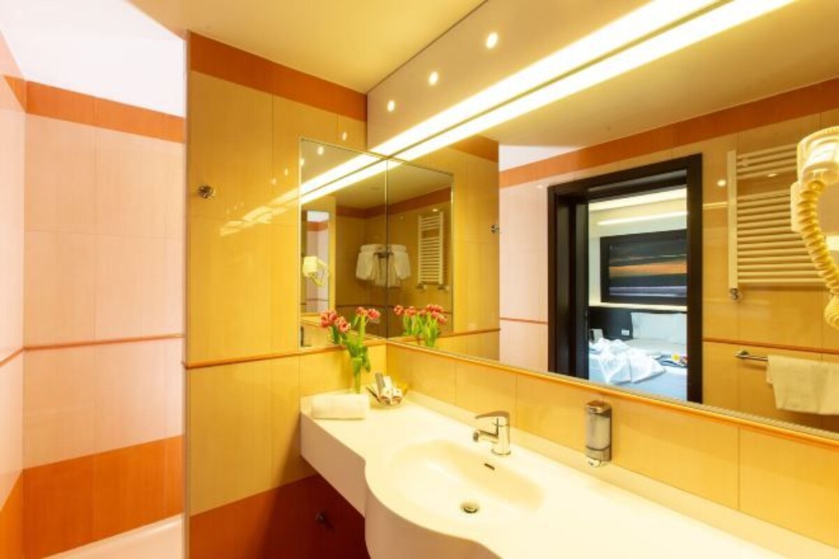 Een moderne badkamer met een grote spiegel, een wit wastafelmeubel en een handdoekrek.