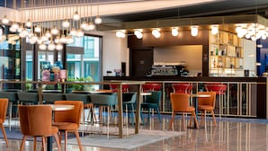 Un café moderno con zona de bar, mesas y una máquina de café.