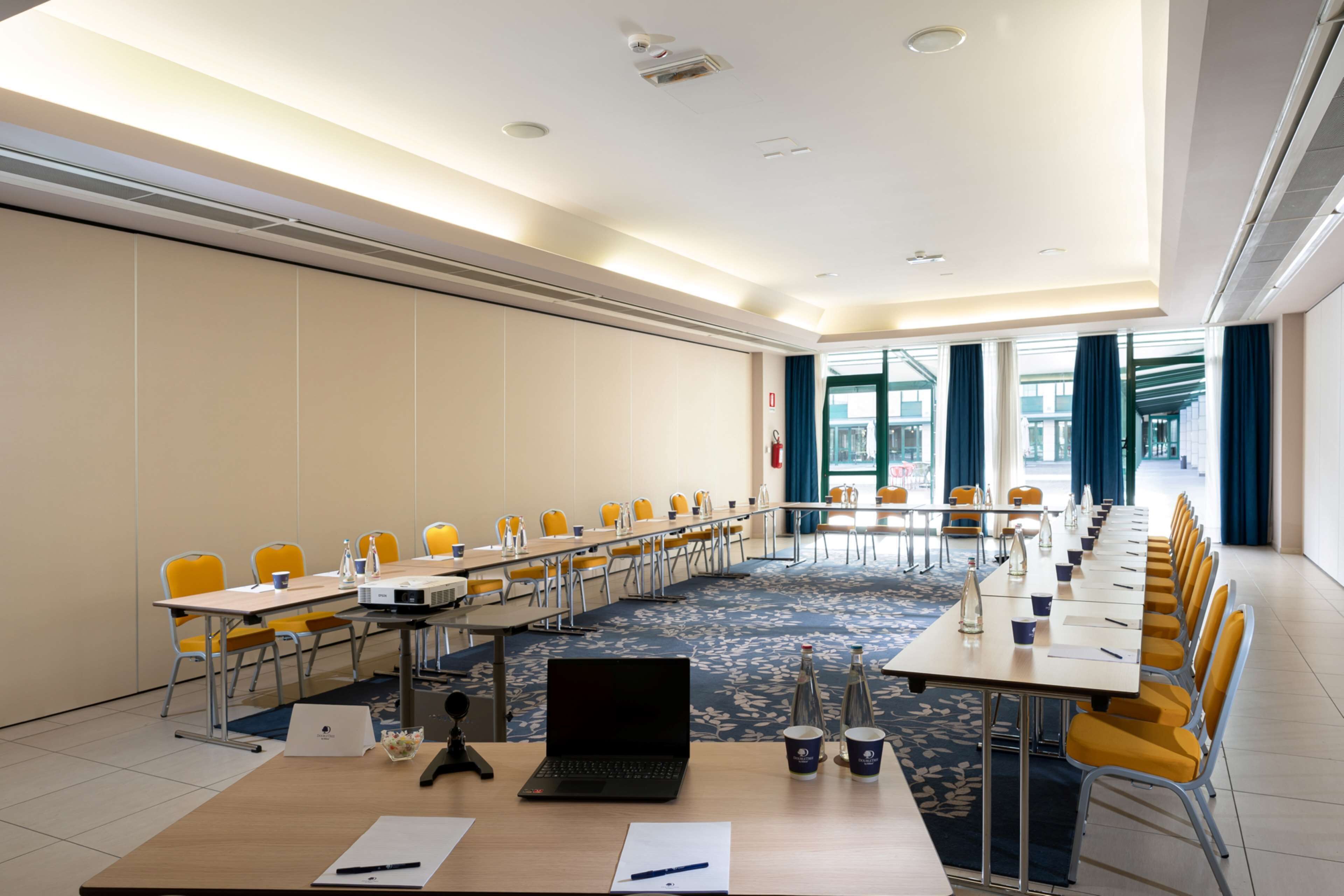 A conference room with a long table, yellow chairs, and a laptop on the table.