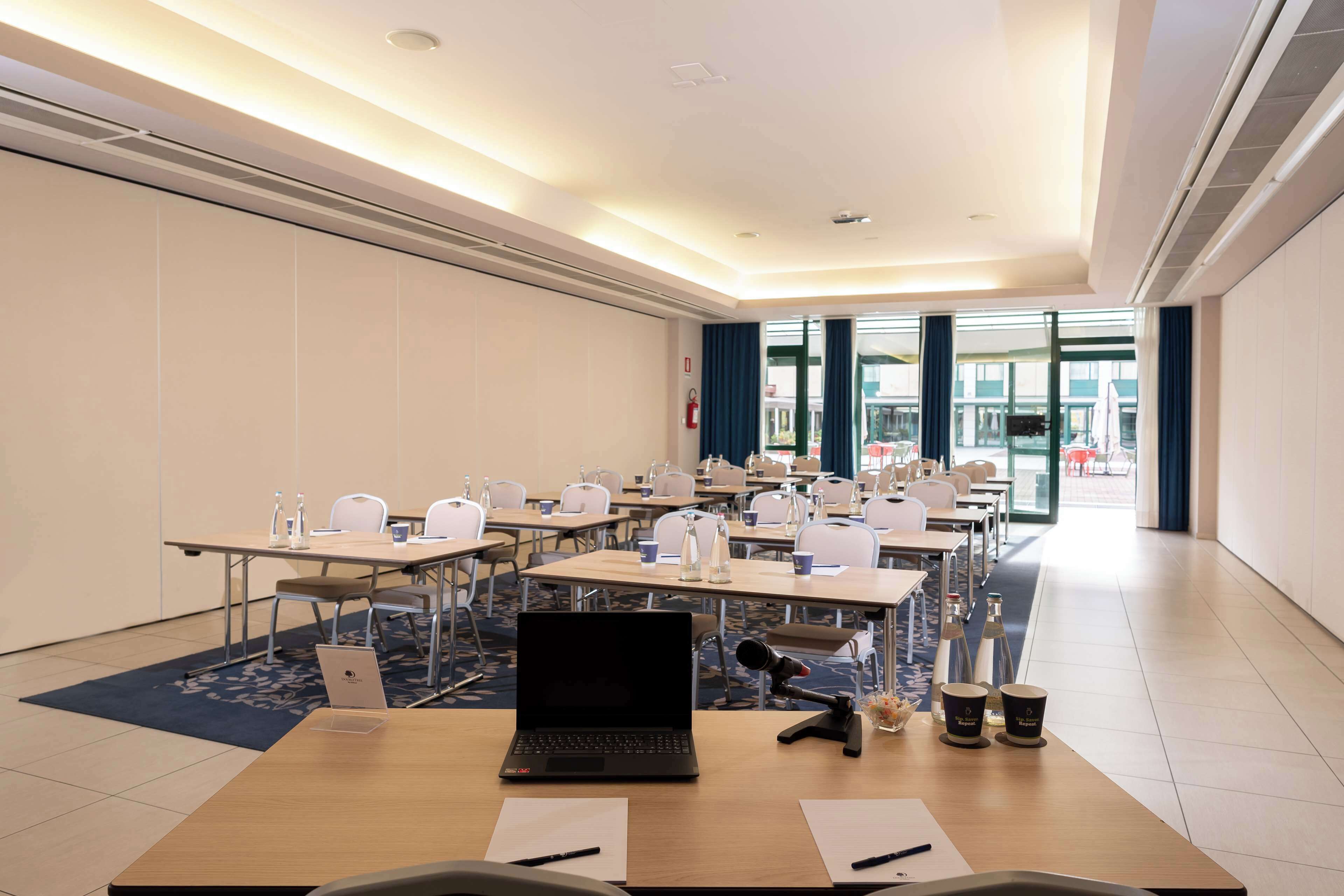 A conference room with multiple tables, chairs, and a laptop.