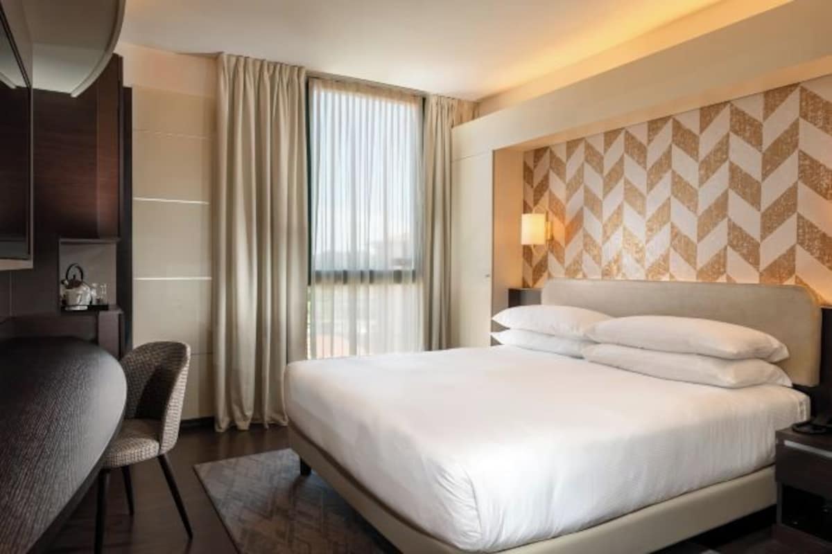 A hotel room with a large bed, a desk, and a chair.