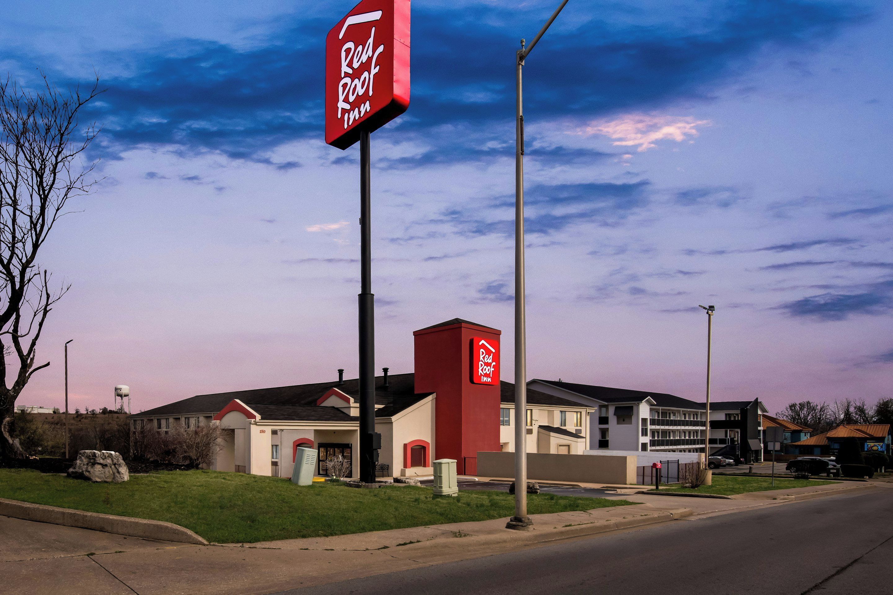 A Red Roof Inn with a prominent red sign, a parking lot, and a building with a flat roof.